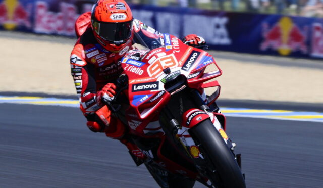 Motorcycle racer leaning into a turn on a red race bike covered in sponsor logos (Lenovo, Shell) on a race track Vieira Biker scene