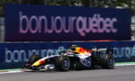 Red Bull Racing Formula 1 car speeding on a race track with a blue advertising barrier in the background.