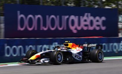 Red Bull Racing Formula 1 car speeding on a race track with a blue advertising barrier in the background.
