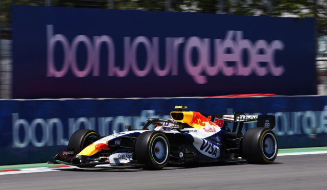 Red Bull Racing Formula 1 car speeding on a race track with a blue advertising barrier in the background.