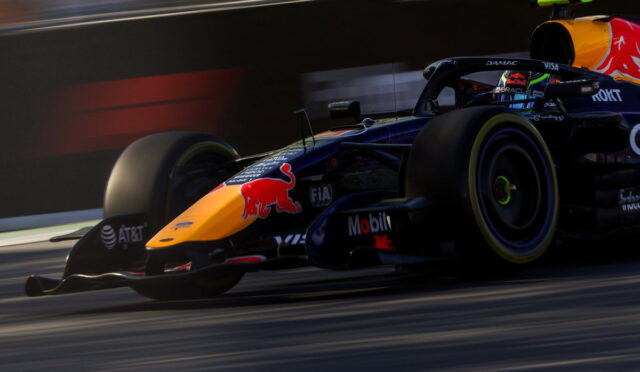 Red Bull Racing Formula 1 car zooming on track, orange nose with Red Bull logo and sponsor decals visible.