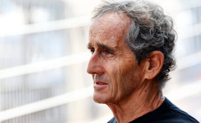 Profile of an older man with gray hair outdoors, wearing a black shirt