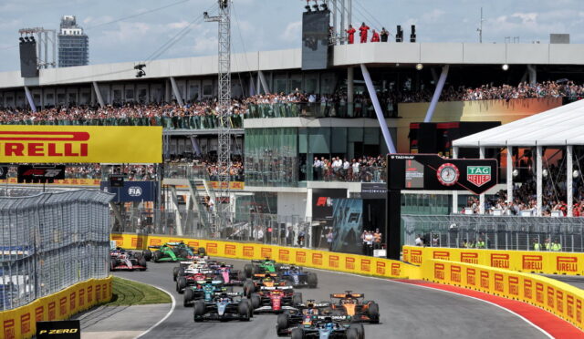 Formula 1 cars race down a street circuit with grandstands full of spectators and prominent sponsor banners (Pirelli).