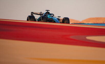 Formula 1 car on a race track, seen from a low angle with blurred red foreground elements in the foreground.
