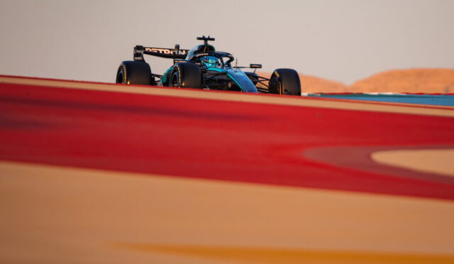 Formula 1 car on a race track, seen from a low angle with blurred red foreground elements in the foreground.