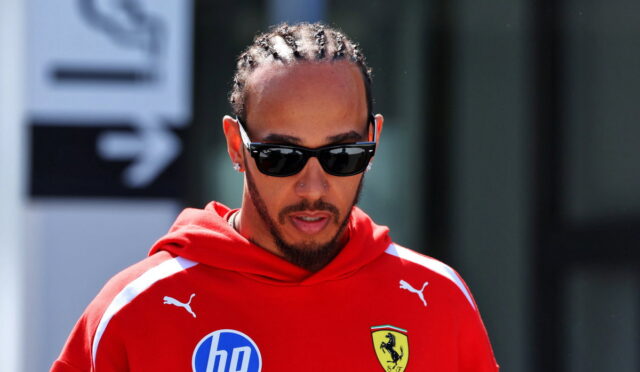 Man with cornrow braids wearing black sunglasses and a red Ferrari hoodie with an HP logo on the chest.