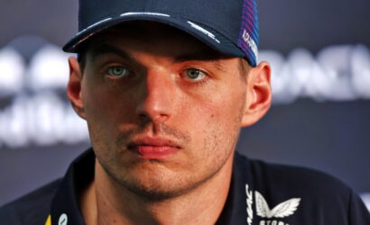 Close-up of a male athlete wearing a dark cap, looking off-camera with a serious expression.