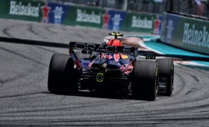 Red Bull Formula 1 car seen from behind on a race track, rear wing with ORACLE text and Heineken banners along the barrier nearby
