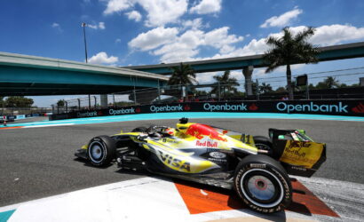 Red Bull Racing Formula 1 car (no. 41) on a sunlit race track, blue sky, with Openbank sponsor banners along the barrier.