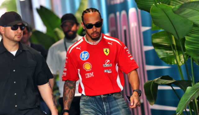 Center: man in red Ferrari shirt with sponsor logos, wearing sunglasses, walking with a security guard in black behind tropical plants.