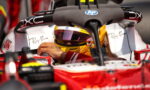 Formula 1 driver with a gold helmet inside a red single-seater, hand resting on the cockpit with sponsor logos visible (Ray‑Ban, HP).