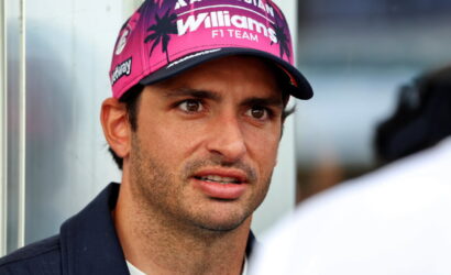 Man wearing a pink Williams F1 Team cap looking slightly to the right during an interview.