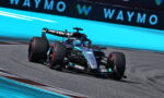 Mercedes-AMG Petronas Formula One car taking a left turn on a race track, blue run-off wall in the background.