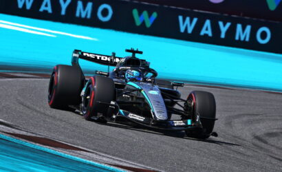 Mercedes-AMG Petronas Formula One car taking a left turn on a race track, blue run-off wall in the background.