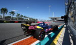Formula 1 car in the Miami Grand Prix pit lane under a clear blue sky with palm trees in the background.
