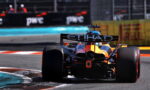 Rear view of a Formula 1 car with orange-blue livery and a large Etihad rear wing on a race track near a turn.