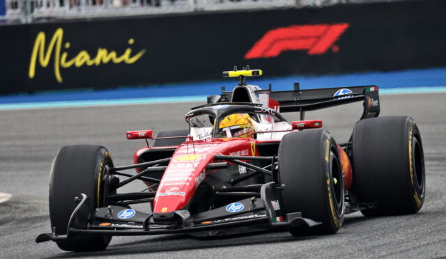 Red Ferrari Formula 1 car speeding on a race track with a Miami sign in the background.