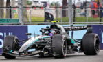 Mercedes-AMG Petronas Formula 1 car on the track, front wing low to the ground, behind safety barriers and fencing.