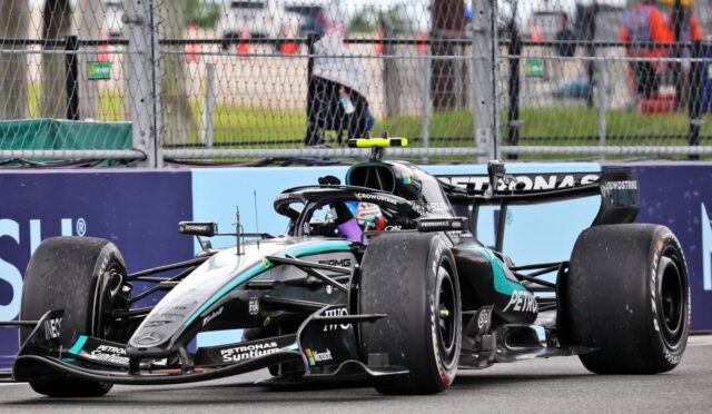 Mercedes-AMG Petronas Formula 1 car on the track, front wing low to the ground, behind safety barriers and fencing.