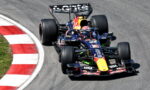 Red Bull Racing Formula 1 car on a sharp curve, racing on a track with sponsor logos visible on the livery.