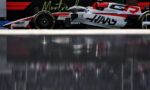 White and red Formula 1 car in the pit lane, sponsor logos visible and slick tires, with a dark backdrop