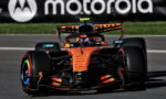 Orange McLaren Formula 1 car racing on a track with a Motorola banner in the background.