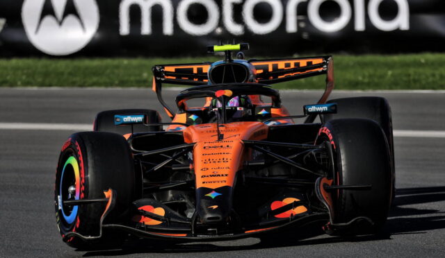 Orange McLaren Formula 1 car racing on a track with a Motorola banner in the background.