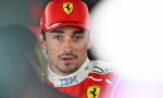 Male racing driver in a red Ferrari cap and suit being interviewed by the media.