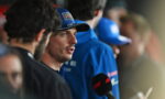 Driver wearing blue cap speaks to press, microphone with red F1 logo in foreground.