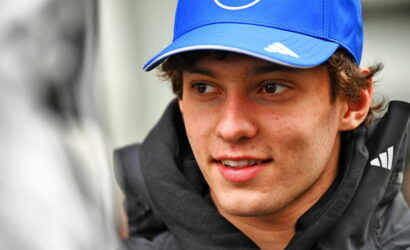 Young man wearing a blue cap with a white logo, looking to the left.