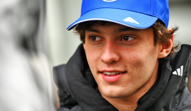 Young man wearing a blue cap with a white logo, looking to the left.