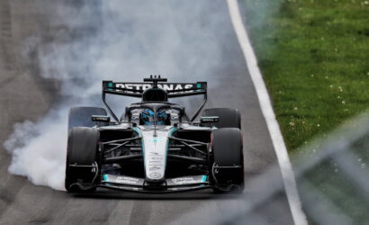 Mercedes-AMG Petronas Formula 1 car drifting with smoke from rear tires on a track, green grass on the side.