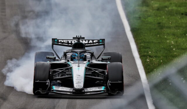 Mercedes-AMG Petronas Formula 1 car drifting with smoke from rear tires on a track, green grass on the side.