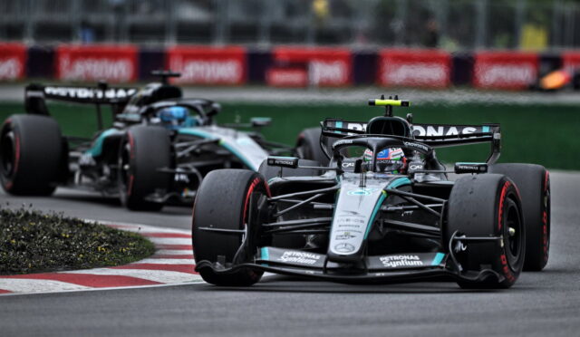 Two Mercedes Formula 1 cars navigate a tight corner on the race track, foreground car leading with Petronas logos in view.