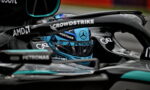 Close-up of a Mercedes Formula 1 cockpit with a blue helmet and sponsor logos, including Petronas, AMD, and CrowdStrike.