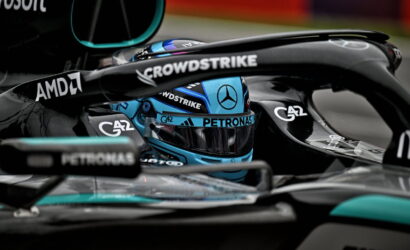 Close-up of a Mercedes Formula 1 cockpit with a blue helmet and sponsor logos, including Petronas, AMD, and CrowdStrike.