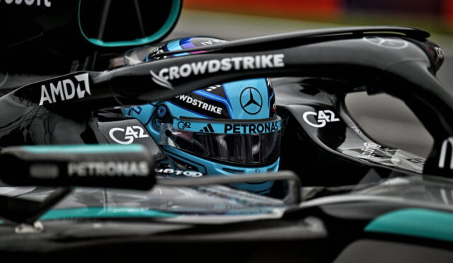 Close-up of a Mercedes Formula 1 cockpit with a blue helmet and sponsor logos, including Petronas, AMD, and CrowdStrike.