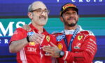 Two Ferrari Formula 1 drivers pose on the podium with medals after a race, smiling at the camera.