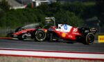 Two red Ferrari Formula 1 cars racing side by side on a track, with sponsor logos like HP and Shell visible.