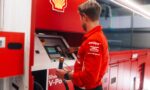 Man in a red Shell uniform uses a payment terminal at a red service kiosk indoors.