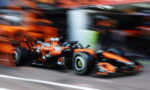 Blurry orange and black Formula 1 car speeding in the pit lane, motion blur emphasis on speed and race environment