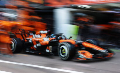 Blurry orange and black Formula 1 car speeding in the pit lane, motion blur emphasis on speed and race environment