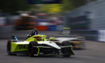 Neon-yellow Formula 1 car speeds along a race track, with a second car blurred in the background during a tight corner.