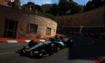 Two Formula 1 cars race along a Monaco street circuit beside stone walls, with spectators on a terrace above the track.