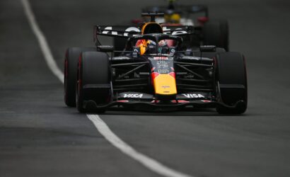 Front view of a Red Bull Racing Formula 1 car racing toward the camera, nose and front wing in focus on a dark track with a white line left of center.