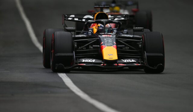Front view of a Red Bull Racing Formula 1 car racing toward the camera, nose and front wing in focus on a dark track with a white line left of center.