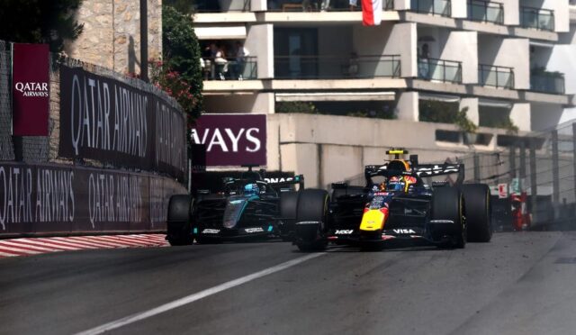 Two Formula 1 cars race side by side on a city street circuit with sponsor barriers and a building backdrop, Qatar Airways banners visible.