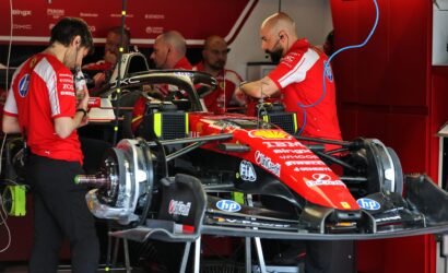 Ferrari Formula 1 pit crew servicing a red race car in the garage.