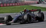 Mercedes Formula 1 car speeding on a race track with a bright yellow cockpit camera, blurred barriers in the background.