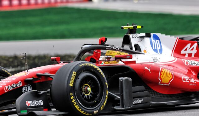 Red Formula 1 car on the track, close-up of the cockpit, front wing, and tire with sponsor logos visible.